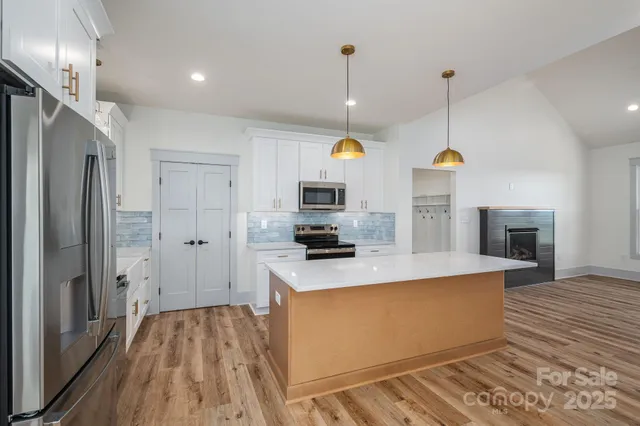 a view of a kitchen with stainless steel appliances granite countertop a refrigerator a oven and a wooden floors