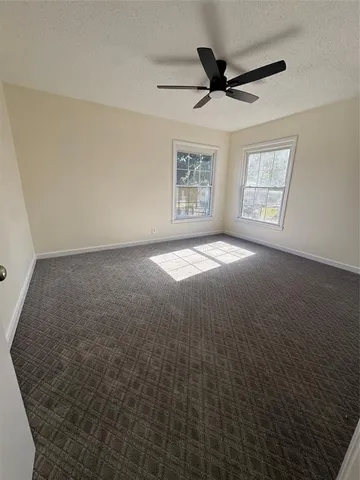 a view of an empty room with a ceiling fan and window