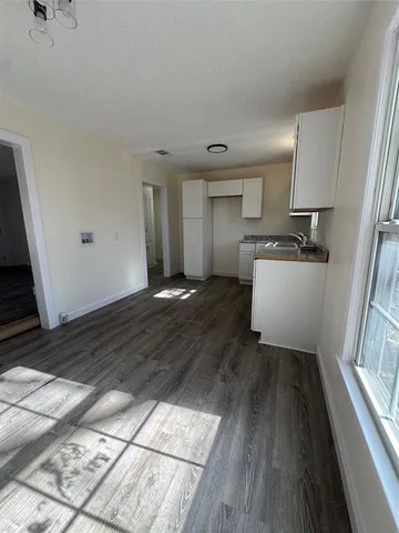 a living room with stainless steel appliances kitchen island granite countertop a sink and wooden floors