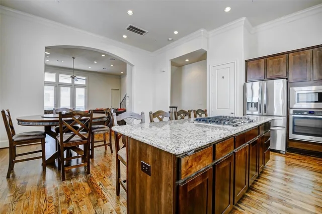 a kitchen with stainless steel appliances granite countertop a kitchen island a stove and a dining table