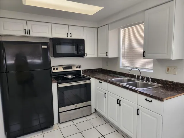 a kitchen with granite countertop a sink stove and microwave
