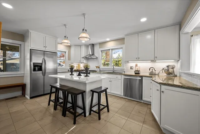 a kitchen with granite countertop stainless steel appliances a sink a stove a refrigerator cabinets and dining table