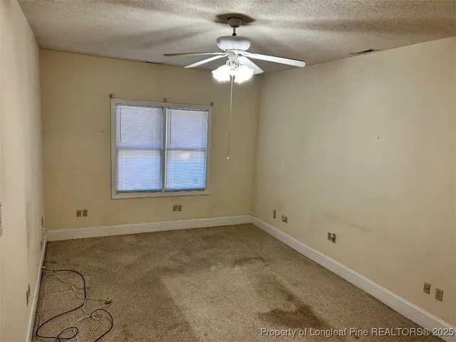an empty room with a chandelier fan and windows