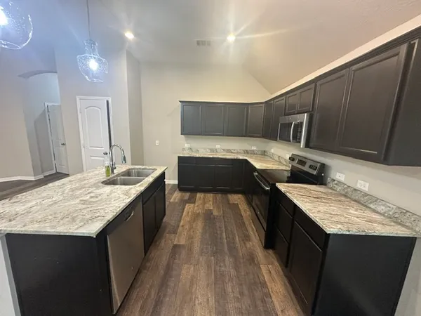a kitchen with kitchen island granite countertop a sink stove and wooden cabinets