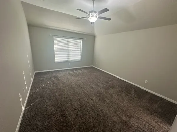 an empty room with a window and a fan