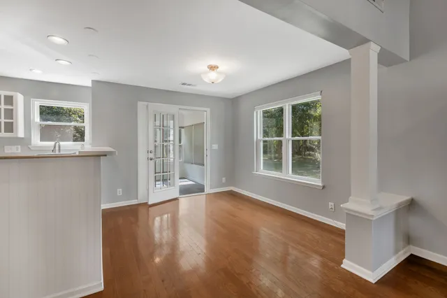 a view of an empty room with wooden floor and a window