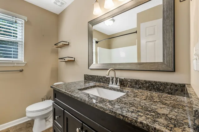 a bathroom with a granite countertop sink and a mirror