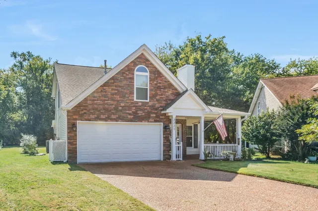 a front view of a house with a garden and trees