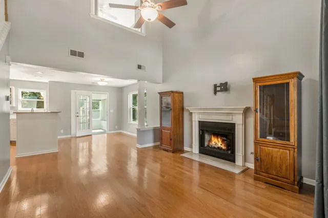 a view of an empty room with wooden floor fireplace and a window
