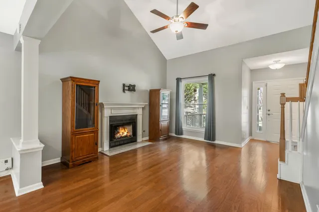 a view of a livingroom with wooden floor a fireplace a ceiling fan and window