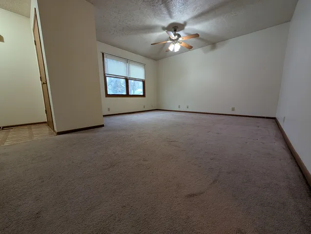 a view of an empty room with a chandelier fan