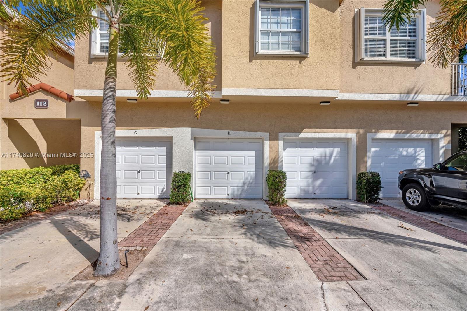 112 Lighthouse Circle, Unit H Tequesta, FL 33469 - Photo 24 of 39 a front view of a house with a yard and garage
