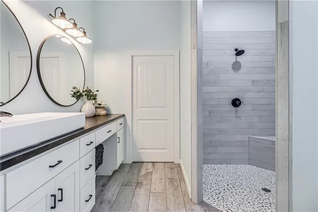 a bathroom with a granite countertop sink a mirror a vanity and shower