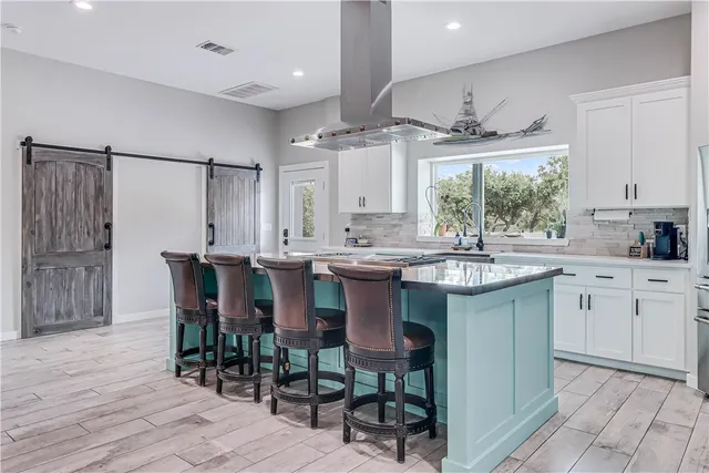a kitchen with stainless steel appliances kitchen island granite countertop a table chairs sink and cabinets