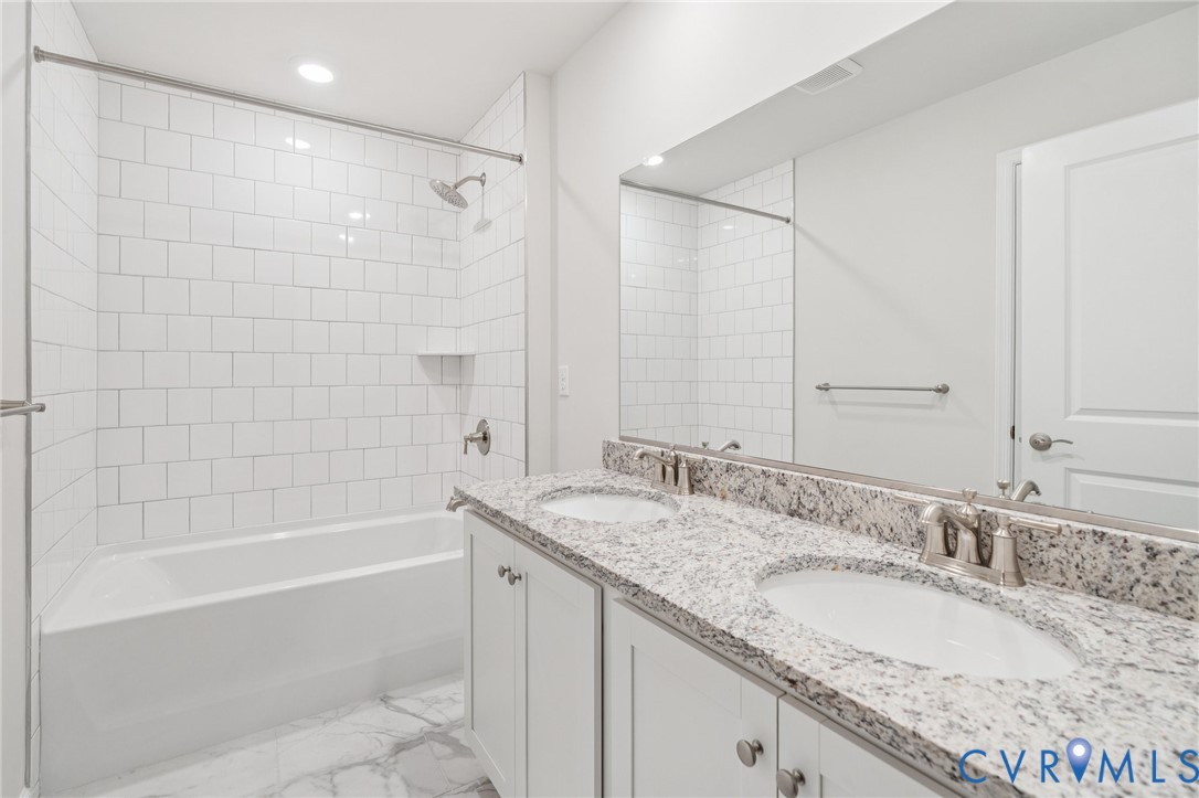 7784 Patriots Way Gloucester, VA 23061 - Photo 20 of 32 a bathroom with a granite countertop double vanity sink and mirror with shower