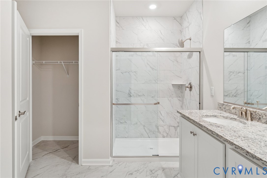 7784 Patriots Way Gloucester, VA 23061 - Photo 29 of 32 a bathroom with a granite countertop sink a shower and a mirror