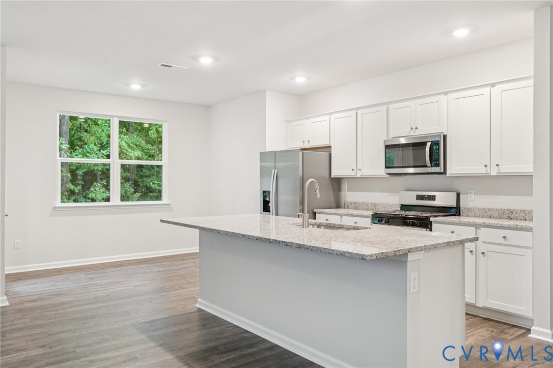 7784 Patriots Way Gloucester, VA 23061 - Photo 5 of 32 a kitchen with stainless steel appliances granite countertop a sink a stove a microwave a refrigerator a window and white cabinets