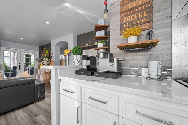 a kitchen with stainless steel appliances granite countertop a refrigerator a stove top oven a sink dishwasher and white cabinets with wooden floor