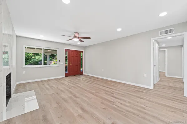 a view of an empty room with a window and wooden floor