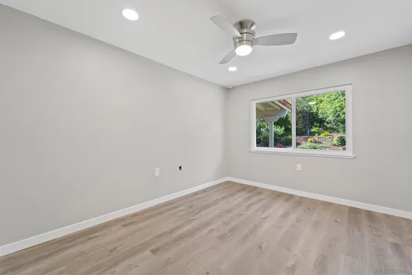 an empty room with a window and a fan