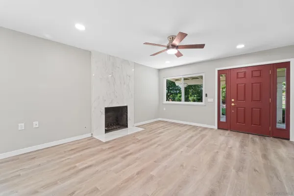 a view of an empty room with a window and a kitchen