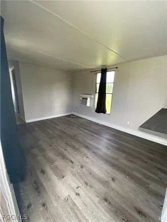 an empty room with wooden floor and window