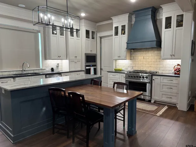 a kitchen with stainless steel appliances granite countertop a sink a stove a table and chairs
