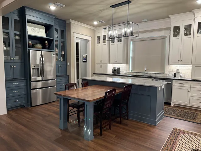 a kitchen with kitchen island granite countertop wooden floors and refrigerator