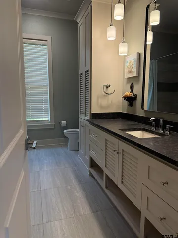 a spacious bathroom with a granite countertop sink toilet and mirror