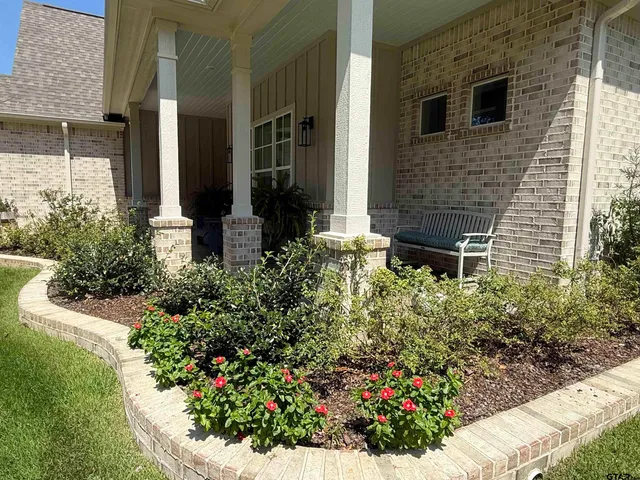 a flower garden in front of a brick house