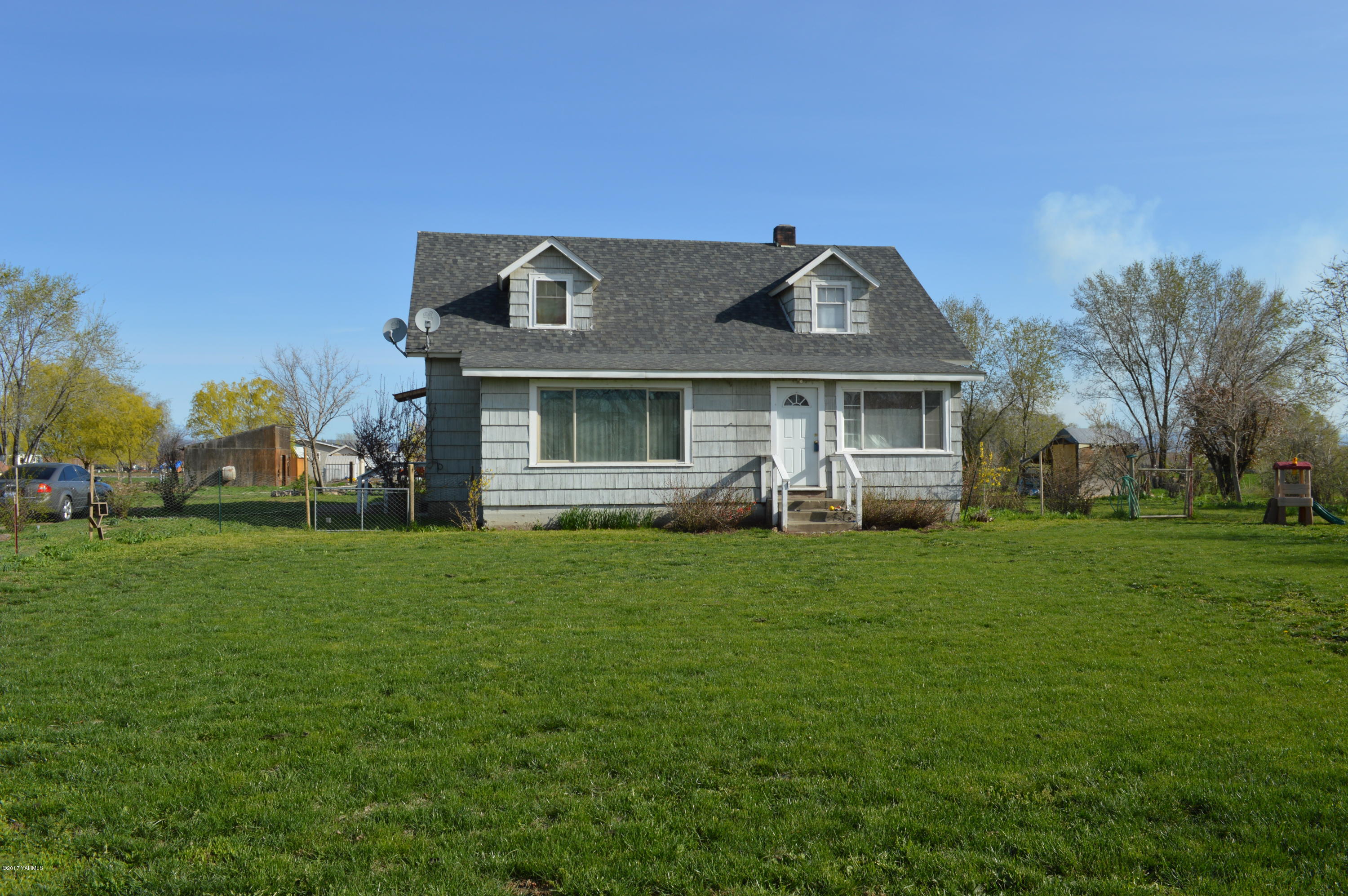 6941 McDonald Road Wapato, WA 98951 - Photo 4 of 24 a front view of a house with a garden and trees