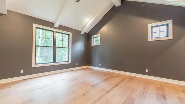 an empty room with wooden floor and windows