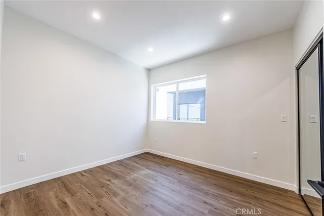 a view of an empty room with wooden floor and closet