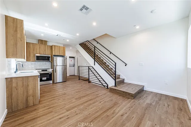 a large kitchen with cabinets wooden floor and stainless steel appliances