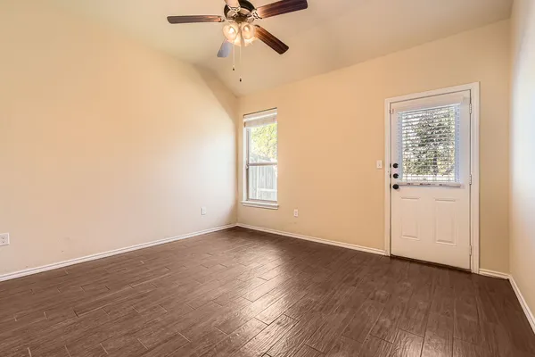 an empty room with wooden floor fan and windows
