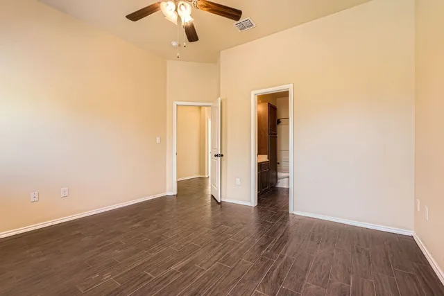 an empty room with wooden floor chandelier fan and closet area