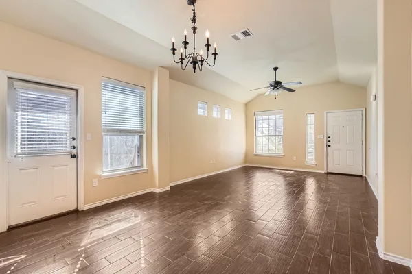 a view of an empty room with a window and wooden floor