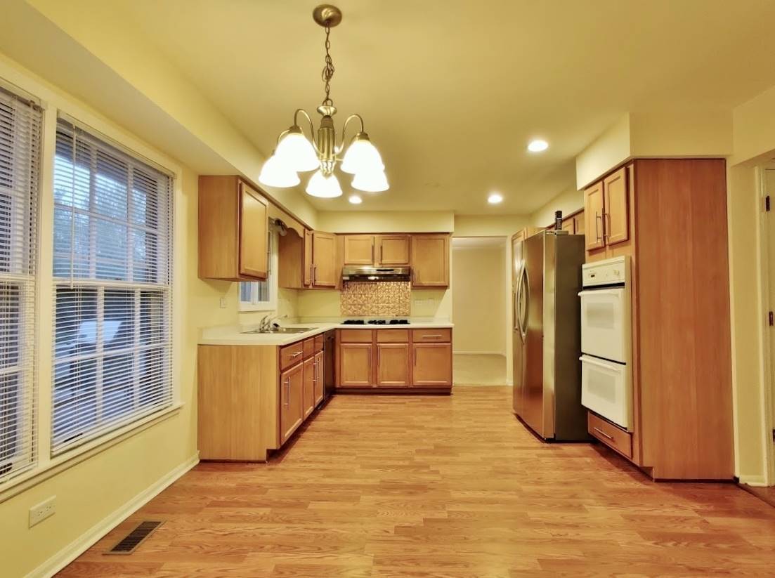 1520 Chippewa Drive Naperville, IL 60563 - Photo 4 of 18 a large kitchen with stainless steel appliances granite countertop a refrigerator a sink dishwasher a stove and a dining table with wooden floor