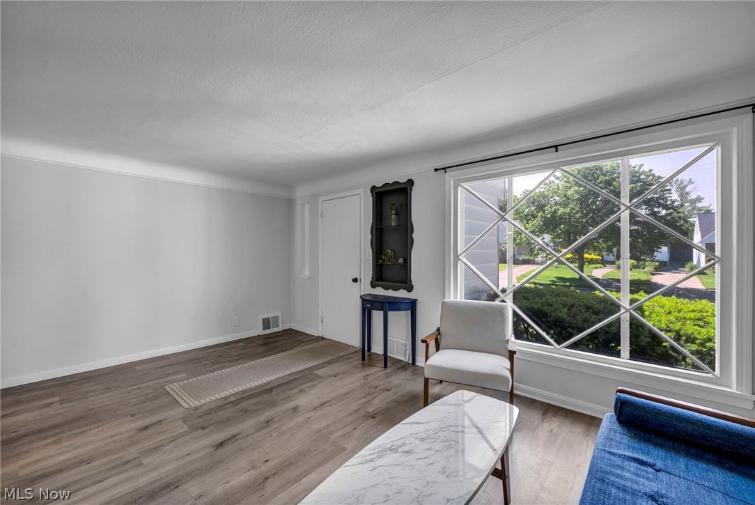 4117 Wyncote Road South Euclid, OH 44121 - Photo 8 of 50 Spacious living area featuring expansive wood-finish flooring, crisp white baseboards, and a large window with diamond-patterned muntins
