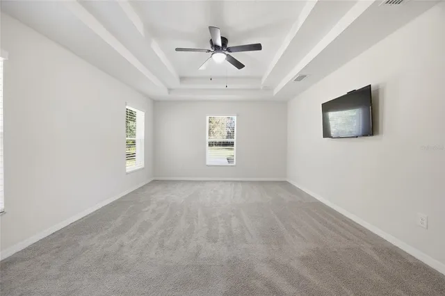 an empty room with windows and ceiling fan
