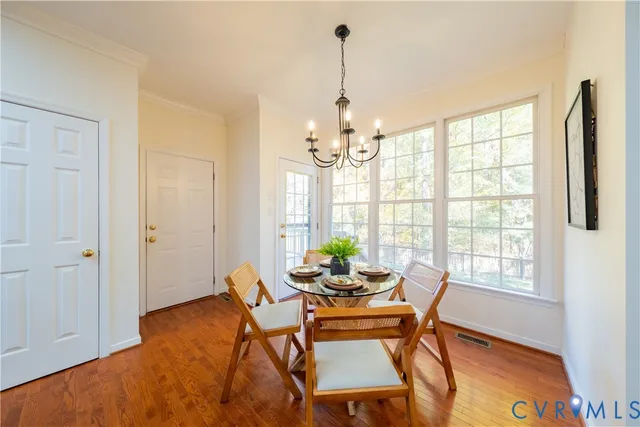 a dining room with furniture a chandelier and wooden floor