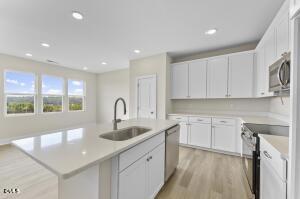 2760 River Meadow Spring Hope, NC 27882 - Photo 16 of 42 a kitchen with white cabinets a sink dishwasher and a stove with wooden floor