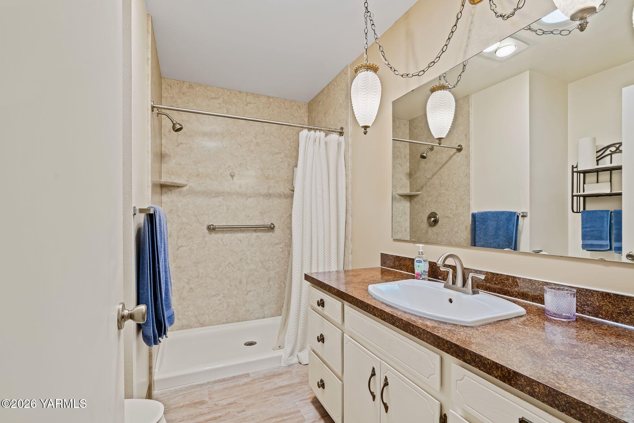 5701 West Chestnut Avenue, Unit 1 Yakima, WA 98908 - Photo 17 of 26 a bathroom with a shower sink and mirror