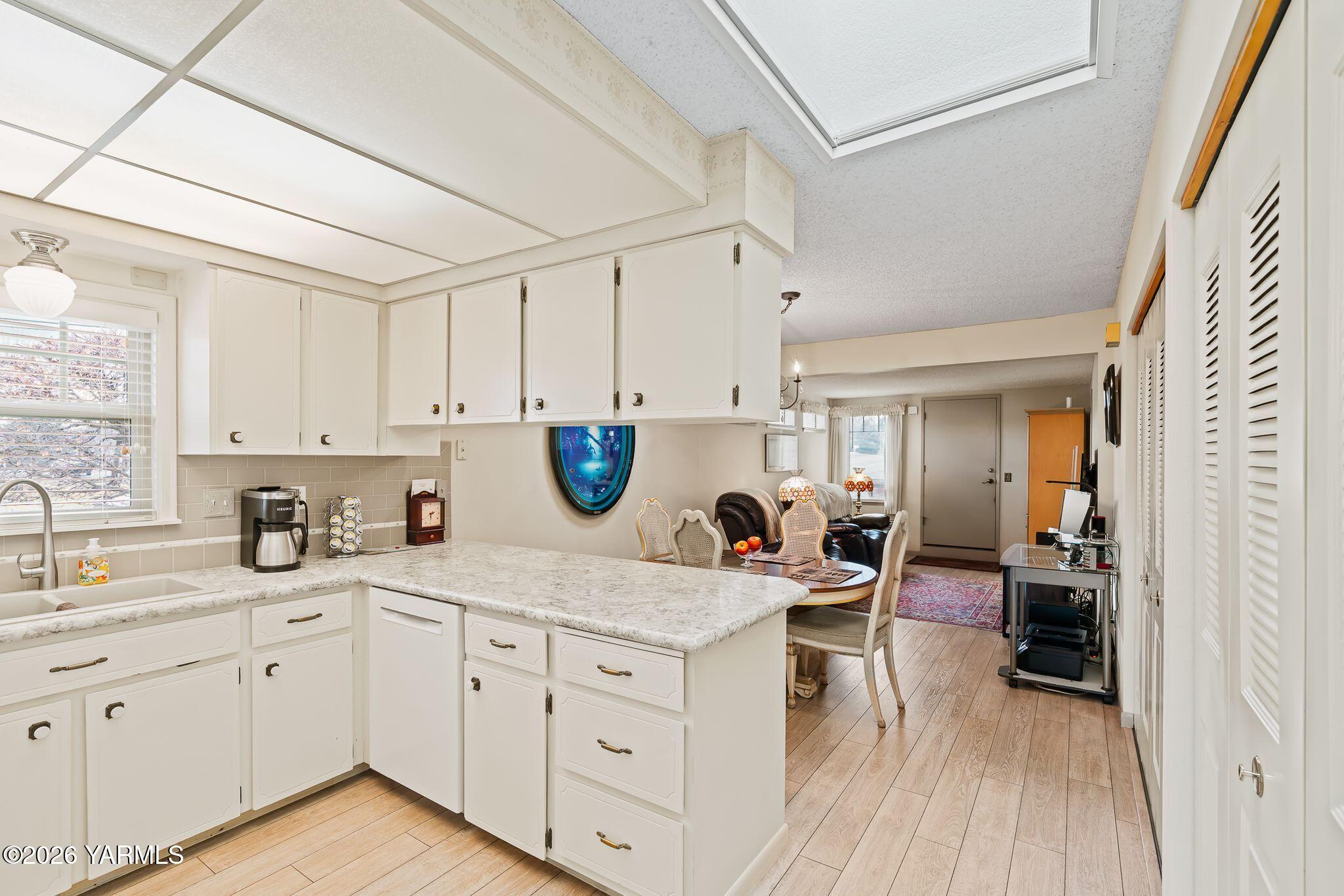 5701 West Chestnut Avenue, Unit 1 Yakima, WA 98908 - Photo 9 of 26 a kitchen with a sink dishwasher a stove and white cabinets with wooden floor