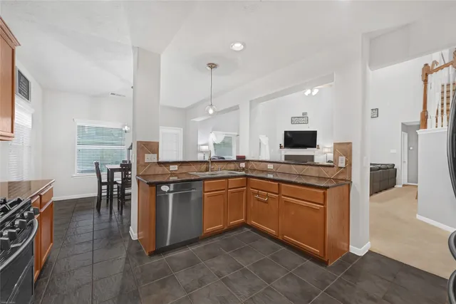 a kitchen with stainless steel appliances granite countertop a stove top oven a sink dishwasher a dining table and chairs with wooden floor