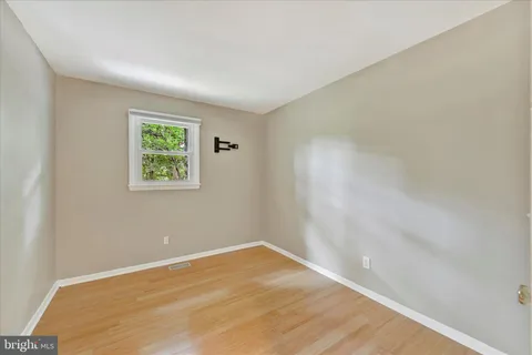 an empty room with a wooden floor and window