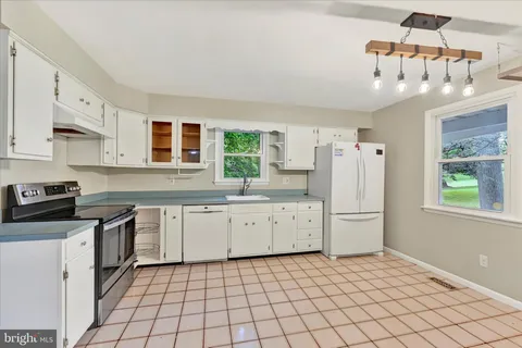 a kitchen with white cabinets and window