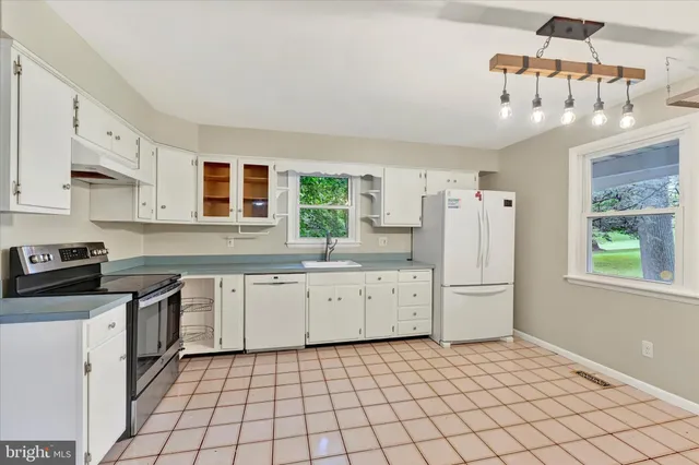 a kitchen with white cabinets and window