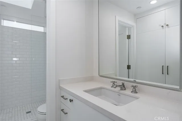 a bathroom with a granite countertop sink a toilet and shower