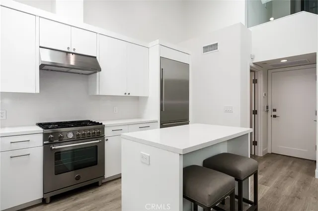 a kitchen with stainless steel appliances a stove a sink and white cabinets